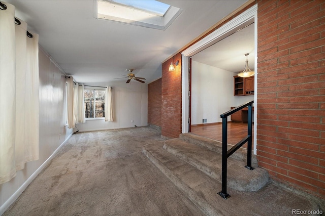 interior space featuring vaulted ceiling with skylight, brick wall, and carpet