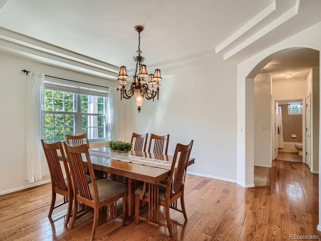 7746 S Valdai Ct, Aurora, CO 80016 - dining room with arched walkways, a chandelier, and light wood-style flooring