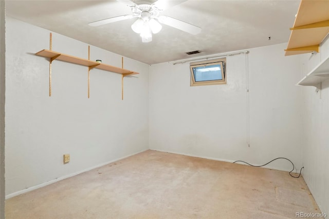 below grade area with ceiling fan, visible vents, and light colored carpet