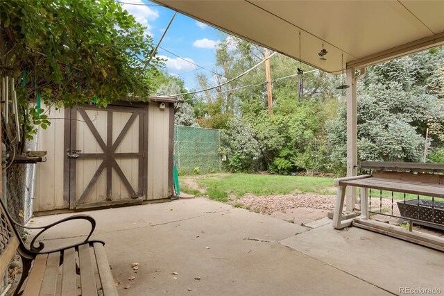 view of patio with a storage unit, an outdoor structure, and fence