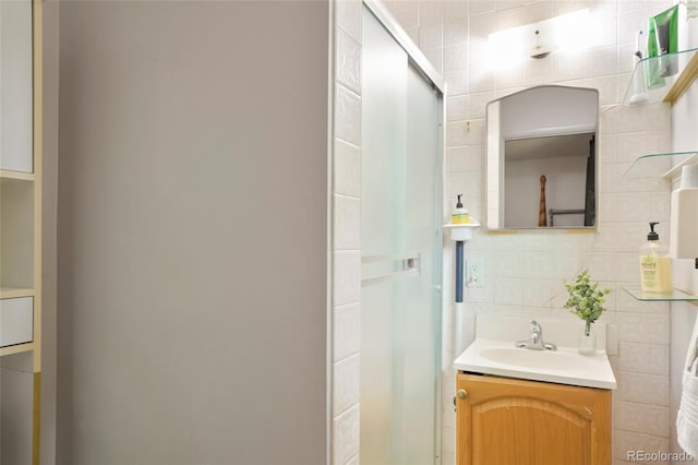 bathroom featuring a stall shower, tile walls, vanity, and decorative backsplash