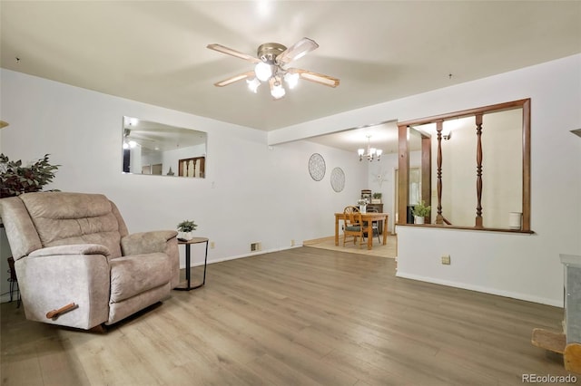 living area featuring visible vents, baseboards, wood finished floors, and ceiling fan with notable chandelier