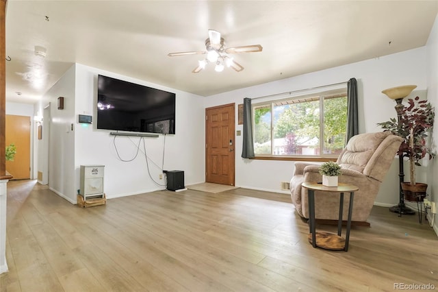 living room featuring ceiling fan, light wood finished floors, and baseboards