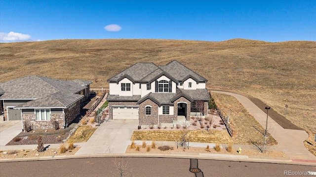 view of front facade featuring driveway, stone siding, a garage, and stucco siding