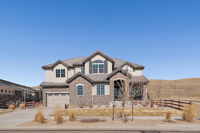 craftsman inspired home featuring stucco siding, concrete driveway, an attached garage, fence, and stone siding