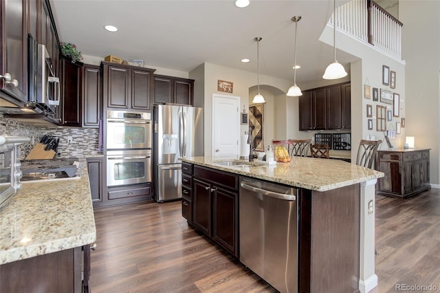 24351 E Alamo Dr, Aurora, CO 80016 - kitchen with appliances with stainless steel finishes, dark brown cabinetry, dark wood finished floors, decorative backsplash, and recessed lighting