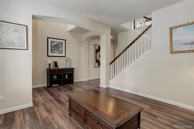 24351 E Alamo Dr, Aurora, CO 80016 - living area with arched walkways, dark wood-style flooring, baseboards, and stairway