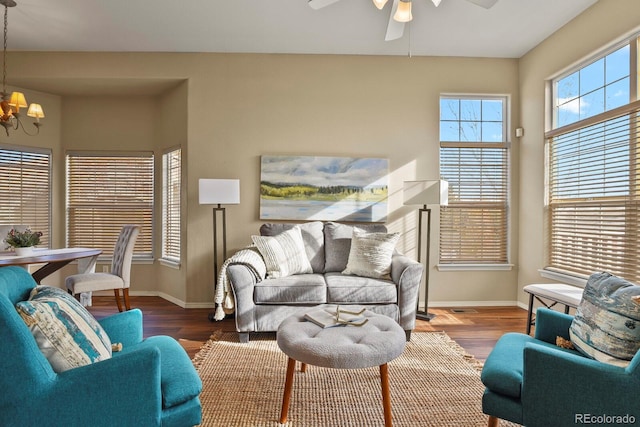 living room with ceiling fan with notable chandelier and hardwood / wood-style floors