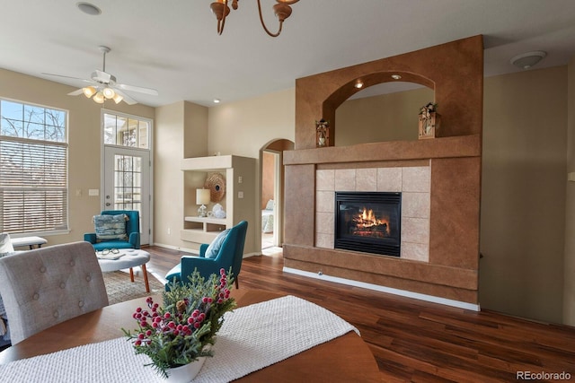 living room with a tile fireplace, dark hardwood / wood-style floors, and ceiling fan