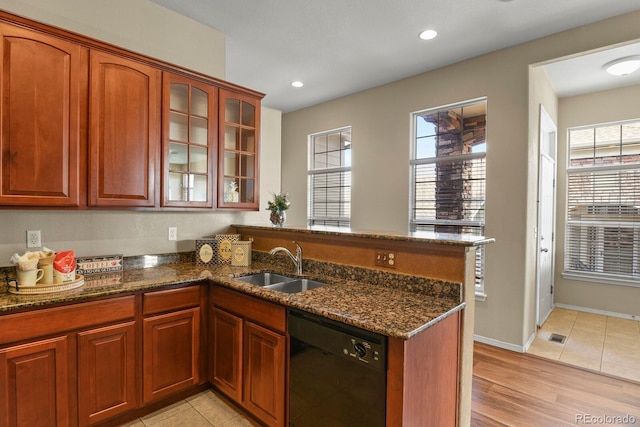 kitchen with dark stone counters, black dishwasher, sink, and kitchen peninsula