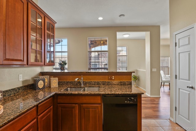 kitchen with a healthy amount of sunlight, black dishwasher, sink, and dark stone countertops