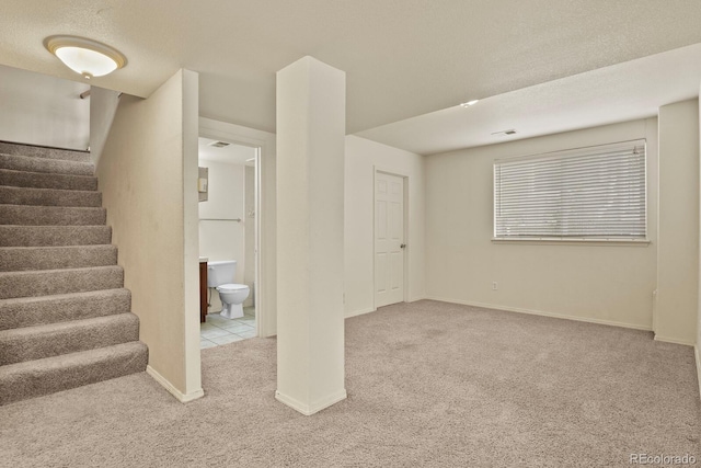 basement featuring light carpet and a textured ceiling