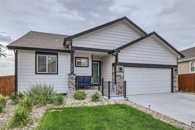 view of front of home featuring a porch, a garage, and a front yard