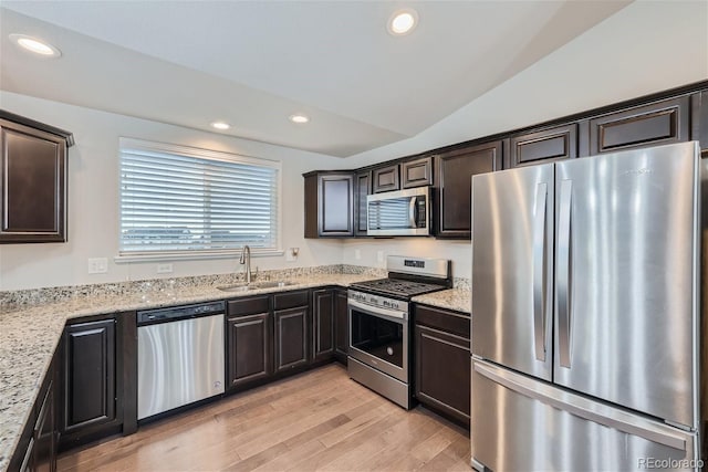 kitchen featuring sink, light stone counters, vaulted ceiling, light hardwood / wood-style flooring, and stainless steel appliances