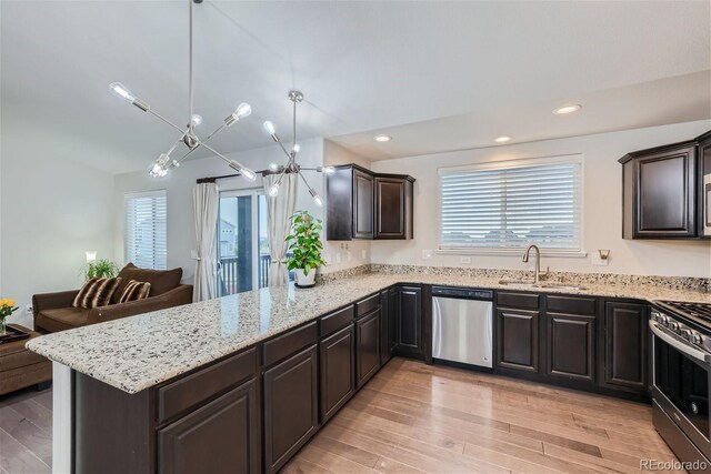 kitchen featuring pendant lighting, sink, light hardwood / wood-style floors, kitchen peninsula, and stainless steel appliances