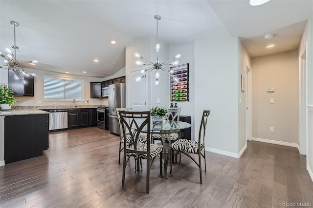 dining area with hardwood / wood-style flooring, lofted ceiling, a chandelier, and sink