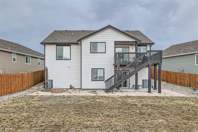 rear view of property featuring a wooden deck, a patio area, and a lawn