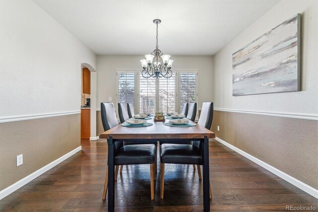 9109 Ironwood Way, Highlands Ranch, CO 80129 - dining room with a textured wall, dark wood-style flooring, arched walkways, and a notable chandelier