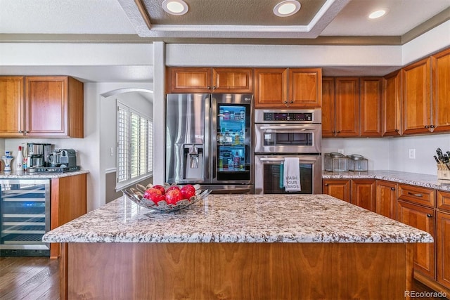 9109 Ironwood Way, Highlands Ranch, CO 80129 - kitchen with appliances with stainless steel finishes, brown cabinetry, light stone countertops, and wine cooler