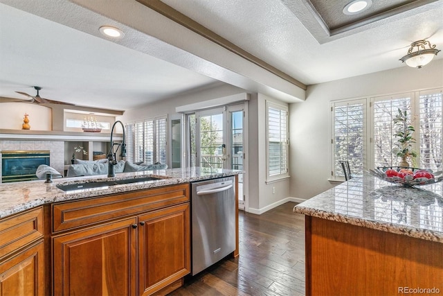 9109 Ironwood Way, Highlands Ranch, CO 80129 - kitchen with dishwasher, baseboards, a sink, brown cabinets, and a tile fireplace