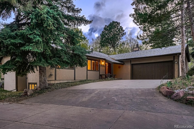 view of front of home with a garage, stucco siding, a chimney, and concrete driveway