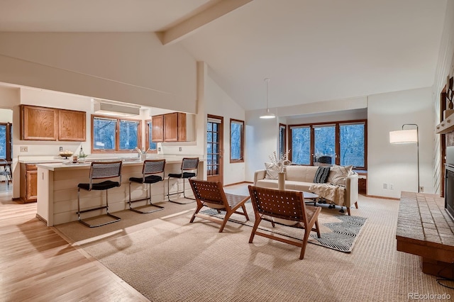 living area with baseboards, light wood finished floors, high vaulted ceiling, and beamed ceiling
