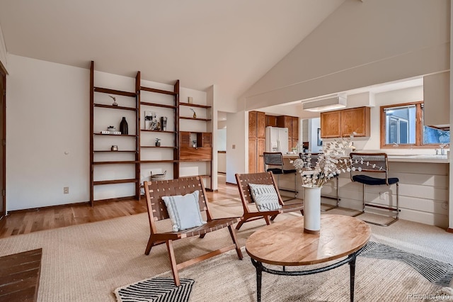 living area with high vaulted ceiling and light wood-style flooring