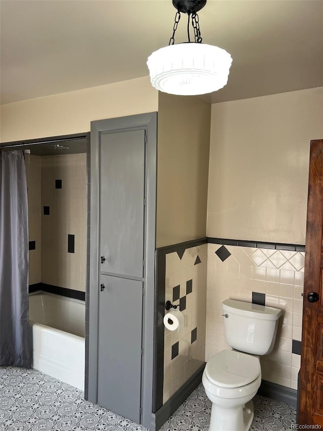 full bathroom with a wainscoted wall, toilet, tile walls, and shower / tub combo