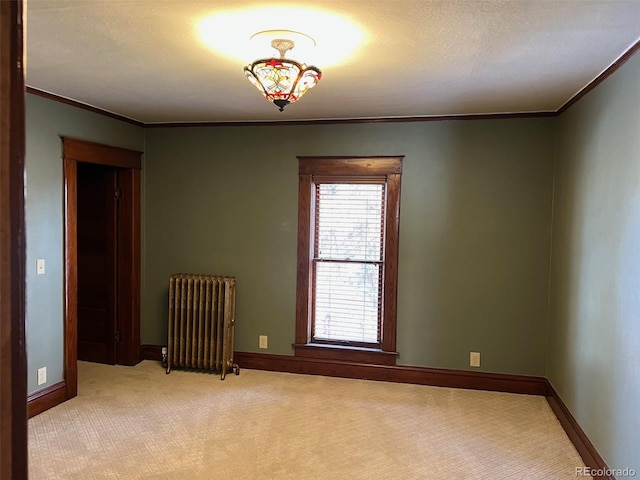 empty room featuring radiator, crown molding, light carpet, and baseboards