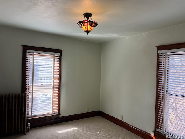 carpeted empty room featuring radiator and baseboards
