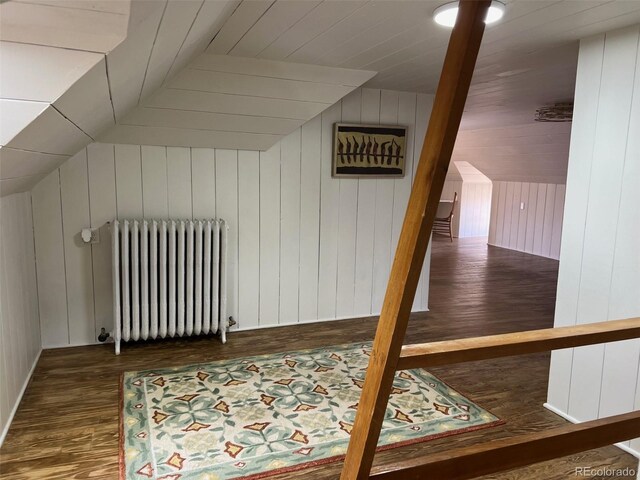 bonus room featuring radiator, wood finished floors, lofted ceiling, and wood walls