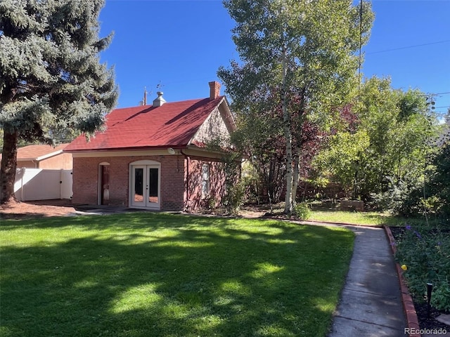 rear view of property featuring french doors, brick siding, and a chimney