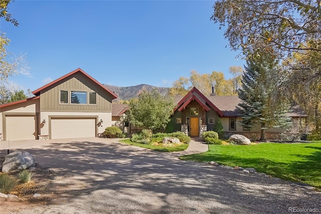 44 Canyon Ct, Eagle, CO 81631 - view of front facade featuring a front lawn, driveway, a mountain view, stone siding, and an attached garage