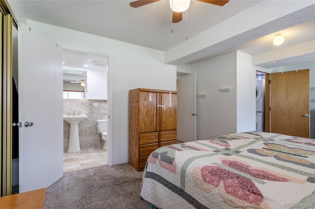 19630 E Purdue Pl, Aurora, CO 80013 - bedroom with stacked washer / drying machine, carpet flooring, a textured ceiling, connected bathroom, and tile walls