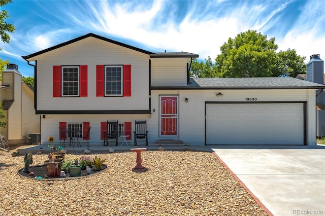 19630 E Purdue Pl, Aurora, CO 80013 - split level home featuring an attached garage, driveway, brick siding, and a chimney