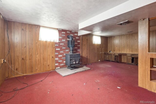 5935 Blanca Ct, Golden, CO 80403 - basement with wooden walls, carpet flooring, a textured ceiling, and a wood stove