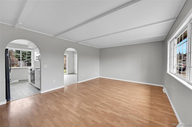 2971 S Sheridan Blvd, Denver, CO 80227 - spare room featuring light wood finished floors, beamed ceiling, baseboards, and arched walkways