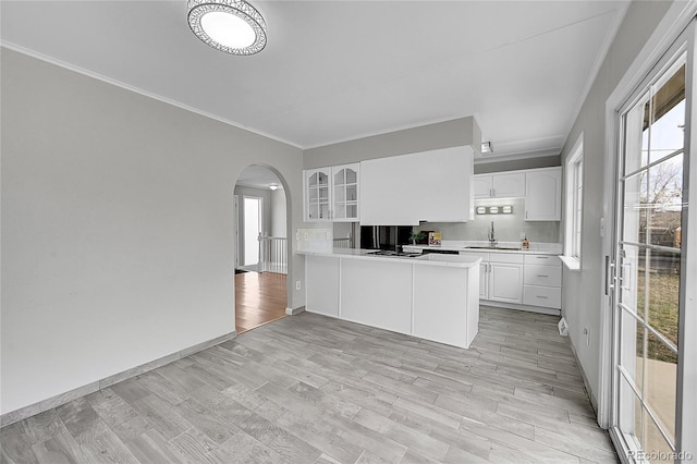 2971 S Sheridan Blvd, Denver, CO 80227 - kitchen with crown molding, a sink, arched walkways, a peninsula, and white cabinetry