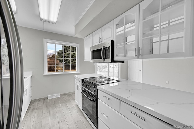 2971 S Sheridan Blvd, Denver, CO 80227 - kitchen featuring stainless steel appliances, light stone counters, white cabinets, light wood finished floors, and glass insert cabinets