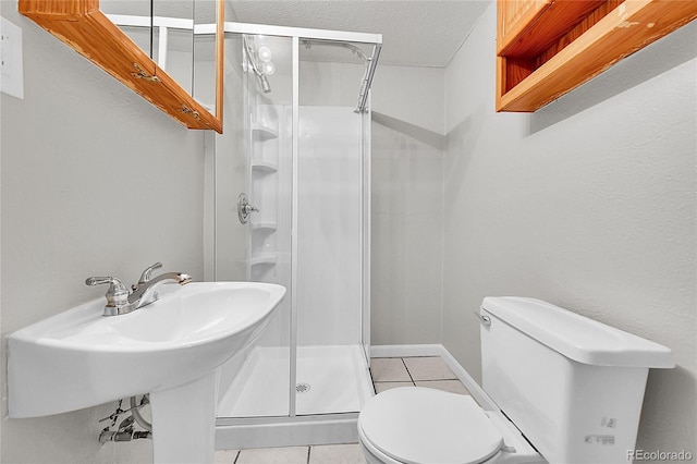 2971 S Sheridan Blvd, Denver, CO 80227 - bathroom with tile patterned floors, toilet, a shower stall, a textured ceiling, and a sink