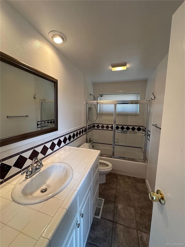 full bathroom with tile patterned flooring, vanity, toilet, and combined bath / shower with glass door