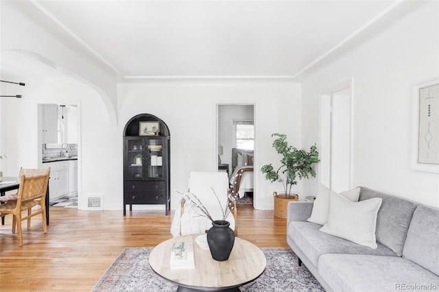 living room with light wood-type flooring and arched walkways