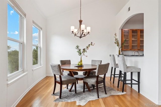 2100 N Humboldt St Unit 302, Denver, CO 80205 - dining room featuring light wood-style floors, a chandelier, baseboards, and arched walkways