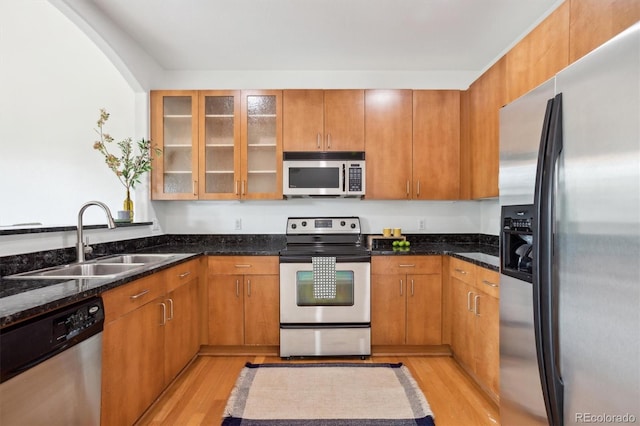 2100 N Humboldt St Unit 302, Denver, CO 80205 - kitchen featuring appliances with stainless steel finishes, a sink, light wood finished floors, and dark stone counters