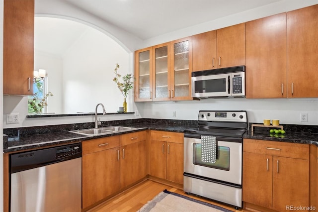 2100 N Humboldt St Unit 302, Denver, CO 80205 - kitchen with stainless steel appliances, a sink, light wood-style floors, dark stone counters, and glass insert cabinets