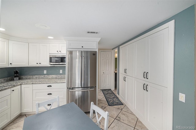6937 S Knolls Way, Centennial, CO 80122 - kitchen featuring appliances with stainless steel finishes, white cabinets, light tile patterned floors, and light stone countertops