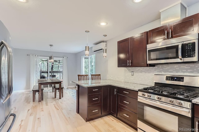 kitchen with light wood-type flooring, pendant lighting, a wall unit AC, stainless steel appliances, and kitchen peninsula