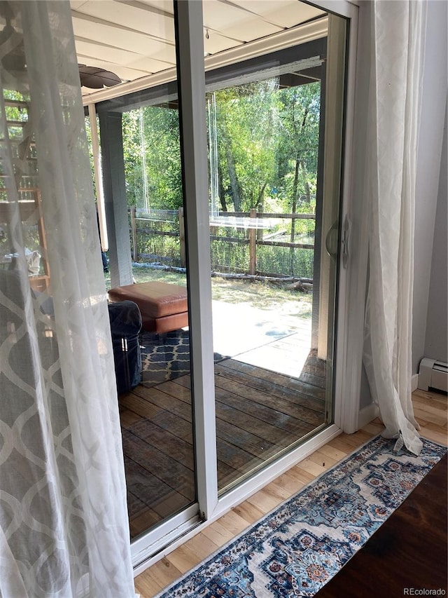 doorway to outside with a baseboard heating unit, a wealth of natural light, and hardwood / wood-style floors