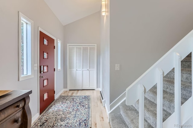 foyer featuring light wood-type flooring, a baseboard heating unit, and lofted ceiling