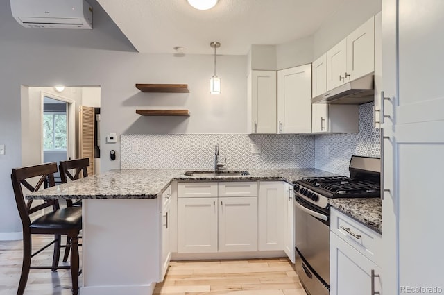 kitchen with white cabinetry, a kitchen bar, kitchen peninsula, sink, and gas range